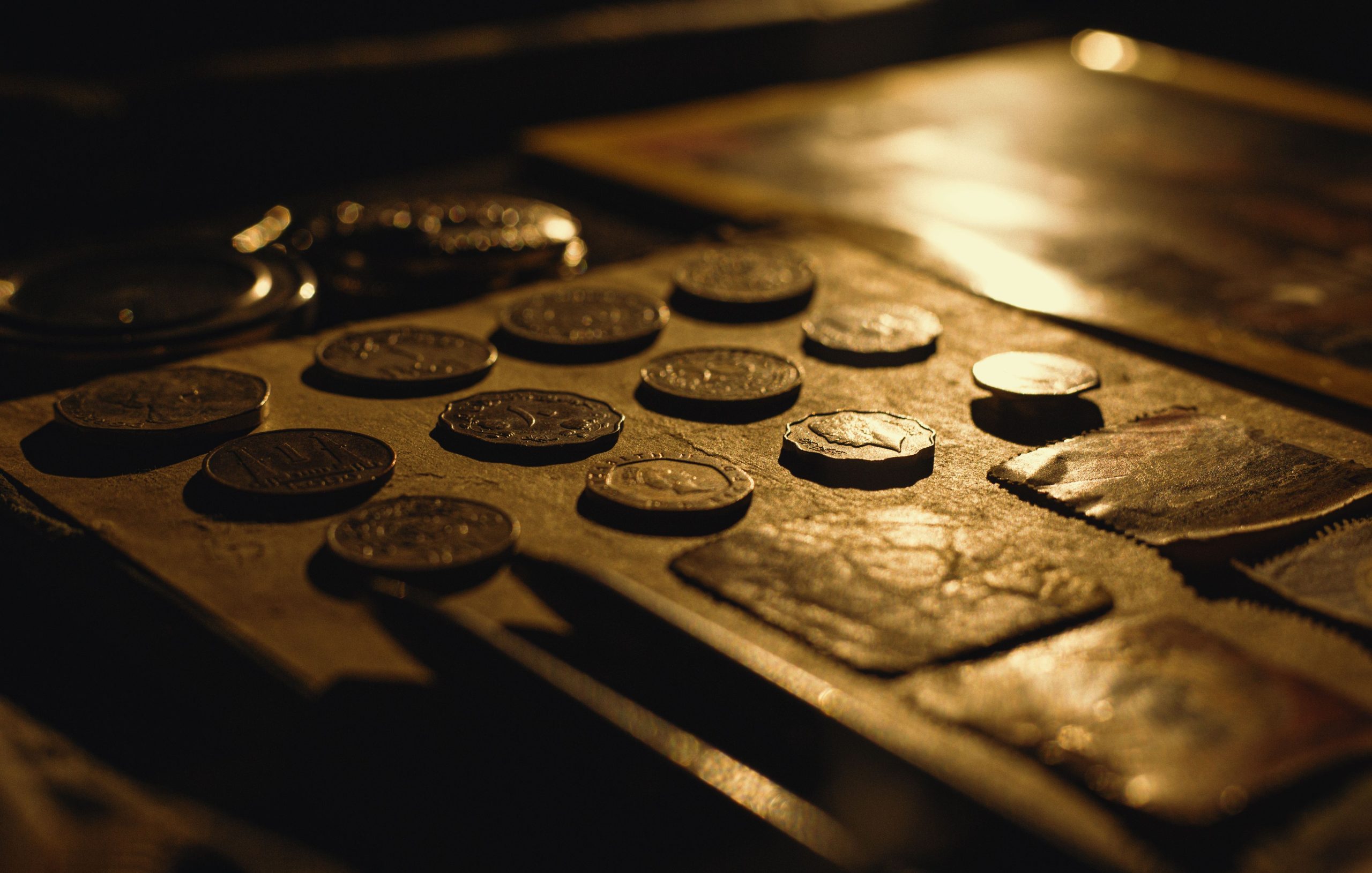 Old coins and an open pocket watch arranged in warm, dramatic light.